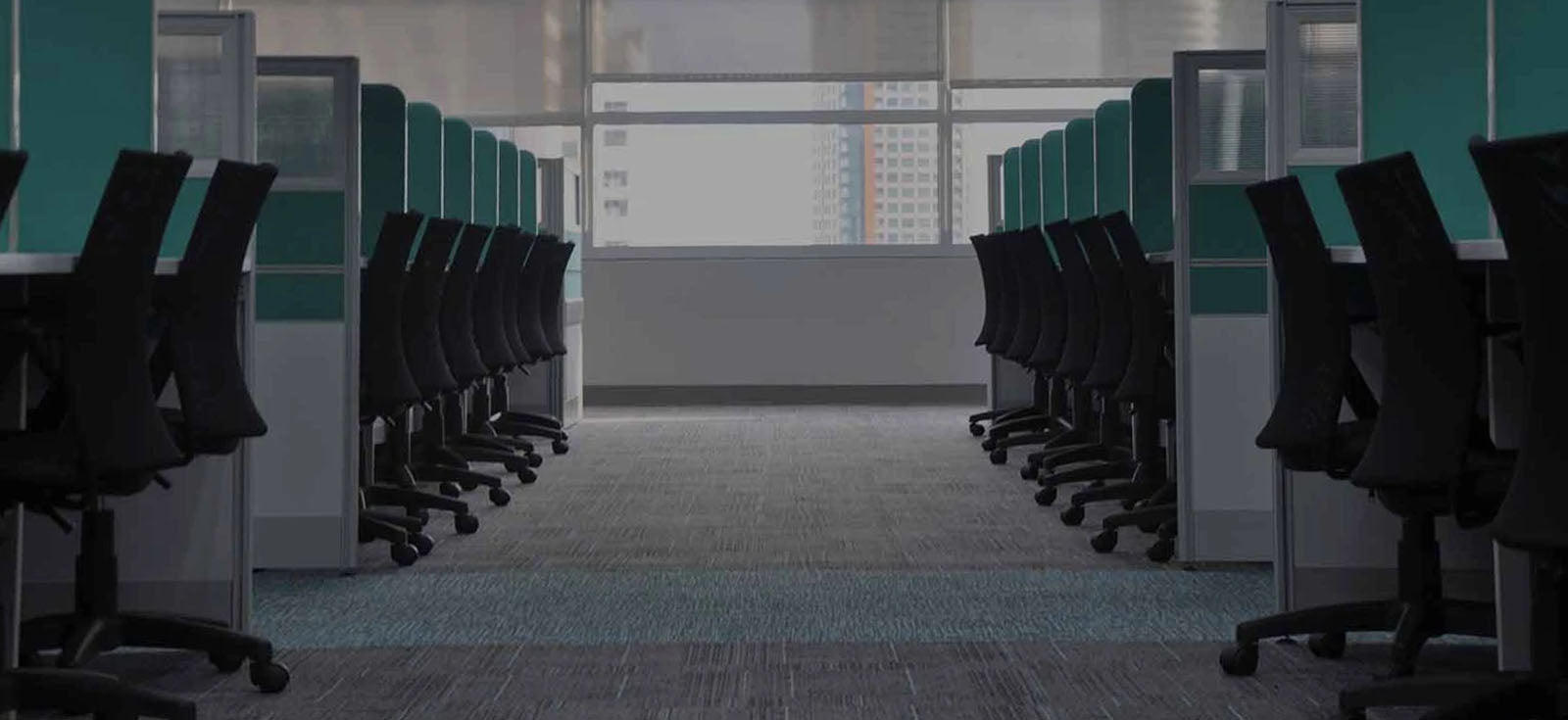 Großraumbüro mit Blick in einen Gang mit Arbeitsboxen und Bürostühlen